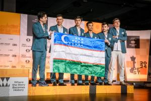 Uzbekistan’s chess team holding the national flag on stage at the 45th FIDE Chess Olympiad in Budapest in 2024.