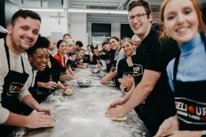Group of adults smiling and making dough together during a Selfup cooking class