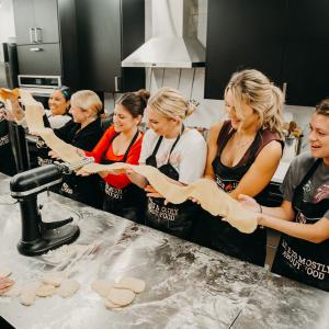 Group of friends laughing and making fresh pasta during a Selfup NYC cooking class.