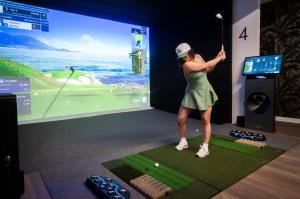 Golfer swinging at a Golf Envy simulator bay
