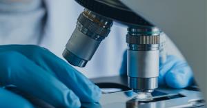 A research slide being moved under a microscope in a laboratory.