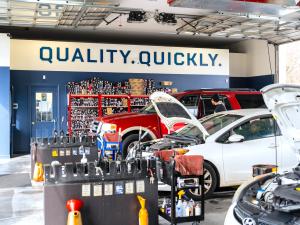 Interior of a Strickland Brothers shop with vehicles being serviced beneath the “Quality. Quickly.” wall display.