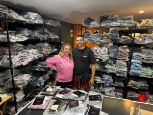 Haden and his mom standing among shelves of packaged Goat Strength and MEROX shorts in their basement workspace