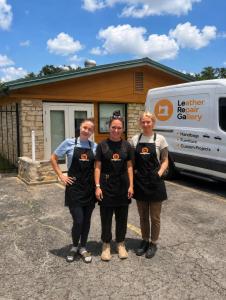 Three Lerega team members wearing branded aprons outside a workshop beside a Leather Repair Gallery van.
