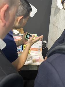 A Dr.Look Ai team member demonstrates the green AI Learning Camera to visitors at the IFA 2026 booth, with product packaging and brochures displayed on the table.