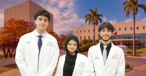 Three ACSOM students in white medical coats stand on the university’s campus in Dominica, with palm trees and academic buildings in the background.