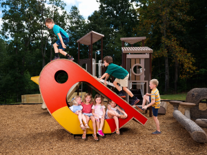 Kids play on a bird-shaped ACRE playground sculpture made of rice hulls
