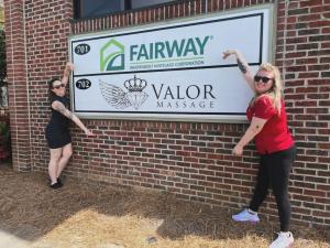 Two Valor Massage® team members outside the Fayetteville, North Carolina practice, pointing to the Valor Massage® business sign.