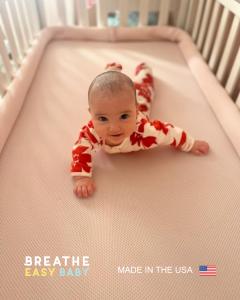 Baby lying on their stomach on a Breathe Easy Baby™ breathable crib mattress inside a crib.