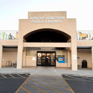 Front entrance of the Apache Junction Public Library with adobe-style architecture and southwestern-themed murals on the upper facade.