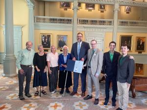 Jim Dolan and other DM community members stand with Sen. Patricia D. Jehlen and Rep. Mike Connolly in the Massachusetts House Chamber.
