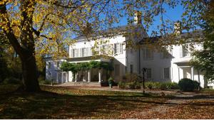 The white colonial revival home as seen from the front in fall, with leaves on the large lawn