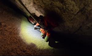 Expedition team transporting a CHASING M2 PRO MAX underwater ROV through a narrow passage inside Raja Santa Cave in Granada, Spain.