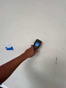 Hand holding a moisture meter against an interior wall at a SoCali job