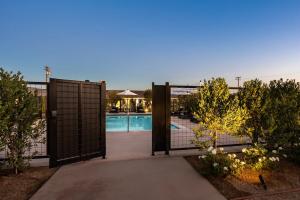 Open courtyard gate leading to Hotel Bayit’s illuminated pool, with lounge chairs, umbrellas and landscaped greenery.
