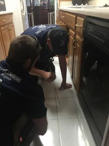 Two Newman's Plumbing technicians conducting a camera pipe inspection in a home kitchen