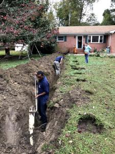 Newman's Plumbing technicians digging a trench in a residential front yard