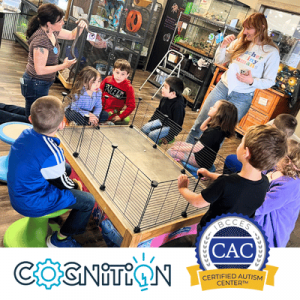 A group of children seated around a table with two adults leading an interactive activity at a Certified Autism Center.