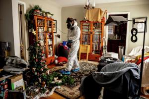 Altadena homeowner wearing protective clothing and a respirator inside a fire-surviving home.