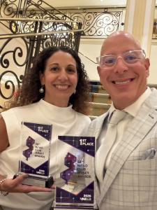 Lynn and Michael Maloney holding two purple-and-clear first-place trophies at the 58th NJ Ad Club Jersey Awards.