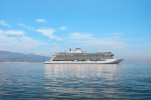 Regent Seven Seas Prestige, kapal pesiar ultra-mewah yang berlayar melintasi perairan biru yang tenang di bawah langit cerah, terlihat dari sisi samping.