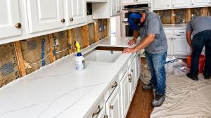 A & R Remodeling and Construction workers installing a new white kitchen countertop.