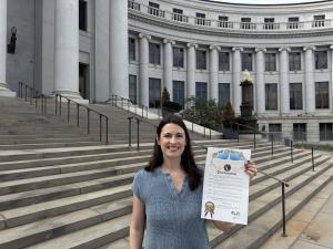Executive Director Lauren Coffaro holds the proclamation by Denver's Mayor.