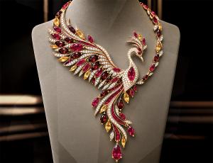 Estela Soler’s "Firebird Phoenix" winning necklace design concept displayed on a jewelry bust, featuring a stylized flying bird with red and yellow gemstones and diamond accents.