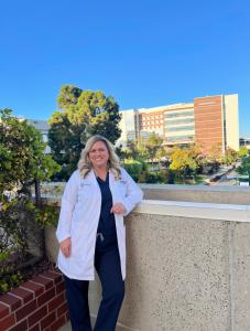 Female physician leaning against wall with hospital background