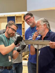 Instructor teaching three apprentices proper tool measurement