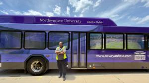 WeDriveU bus operator standing next to Northwestern Hybrid Electric Transit Bus