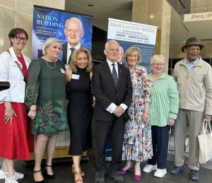 Philip and Heather Ruddock along with community volunteers standing in front of banners at his book launch in Parramatta, Sydney