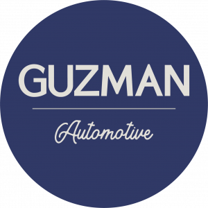 Guzman Automotive circular logo with the company name in white text on a navy blue background.