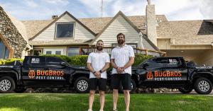 BugBros co-founders Aaron Thomas and Jason Thomas standing outside with BugBros service vehicles.
