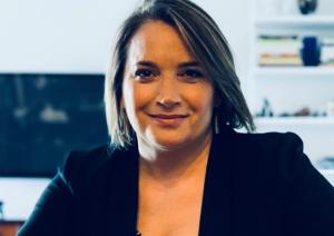 imagine of a smiling woman with dark hair cut into a bob and wearing a black blazer