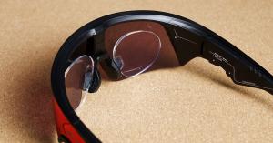 Close view inside an Oakley Meta Vanguard on a cork surface, showing the rimless Banana Sport Optics prescription lenses clipped in on their own nose pad behind the curved Prizm shield.