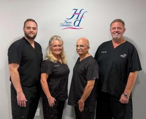 Four dentists in black scrubs standing side by side beneath the Hayes Dentistry logo at the practice's Cookeville, Tennessee office.