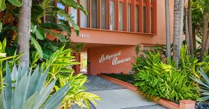 Mid-century building entrance with tropical plants and landscaping.