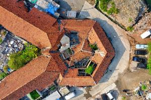 An aerial drone photograph looking straight down at a red-tiled rooftop showing visible damage and construction debris s