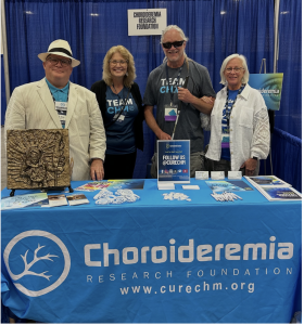 Eric Hartman, CRF Director of Advocacy,Kathi Wagner, CRF Executive Director, and two CHM community members stand together at a Choroideremia Research Foundation informational booth.