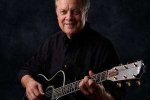 Claude Carmichael With Guitar [(C)2026] Claude Carmichal posing with his guitar in a studio photo setting.