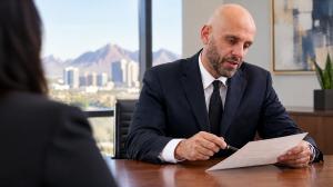 Nasser Abujbarah of Phillips Law Group discussing documents with a client in a Phoenix office.