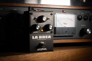 Image shows the La Brea tape saturation pedal leaning up against a vintage reel-to-reel tape deck