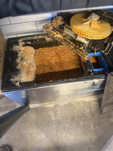 An overflowing restaurant grease trap showing accumulated grease and wastewater buildup that can lead to odors, drainage problems, and kitchen disruptions.