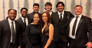Eight Magnolia Acquisitions team members in formal black attire smiling together at the National Conference in Houston.