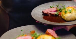 Sliced bavette steak with potato gratin and microgreens, plated at Brugada Kitchen & Bar in downtown Nashville.