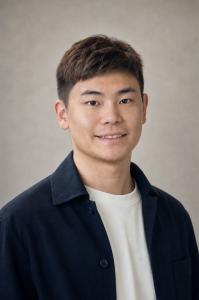 Headshot of Alex Ge, founder and CEO of Addys.AI, wearing a navy jacket over a white T-shirt against a gray background