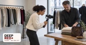 A content creator films a product video with a camera on a gimbal while a boutique owner arranges folded sweaters on a wooden table. The DeepRed logo sits in the lower left with the words Atlanta and New York City.