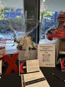 Lovevoo auction donation display at TEDxSaltLakeCity 2026 featuring a curated gift package with Marsicani extra virgin olive oil and Malpighi balsamic vinegar.