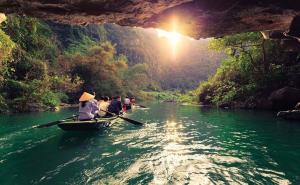 Barque traditionnelle naviguant sur les eaux calmes de Ninh Binh lors d'un circuit Vietnam Cambodge Laos 3 semaines